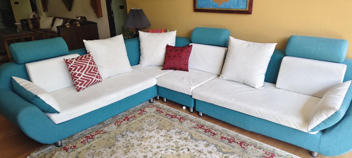 Modern teal and white L-shaped sectional sofa with adjustable headrests, white seat cushions, and decorative throw pillo
