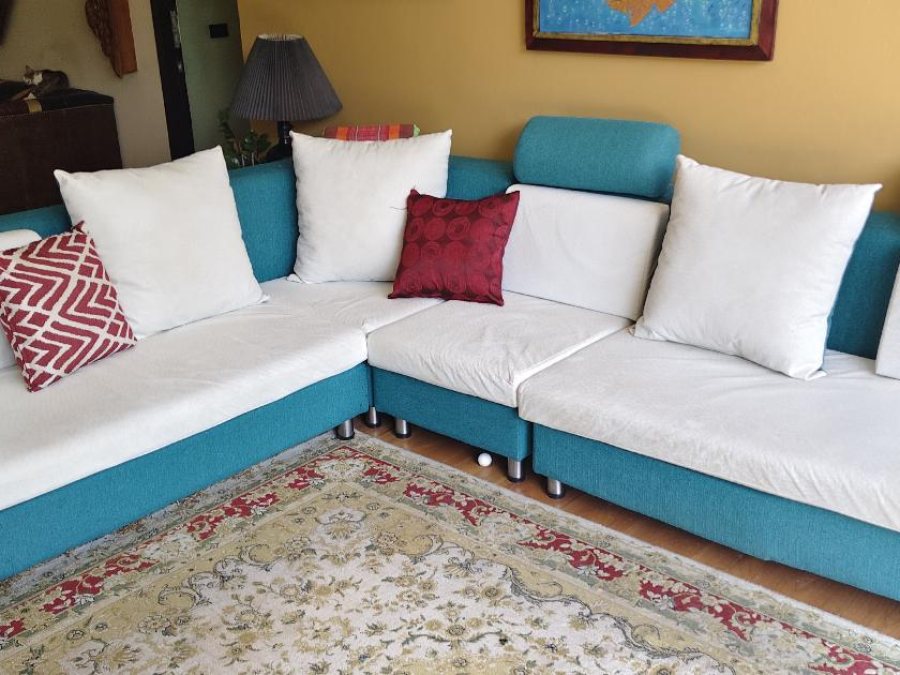 Modern teal and white L-shaped sectional sofa with adjustable headrests, white seat cushions, and decorative throw pillo